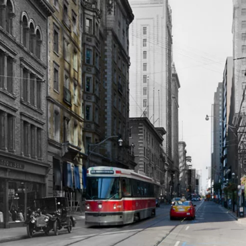 Black and white image with coloured segments of a Toronto streetcar and old fashion car on the same street.